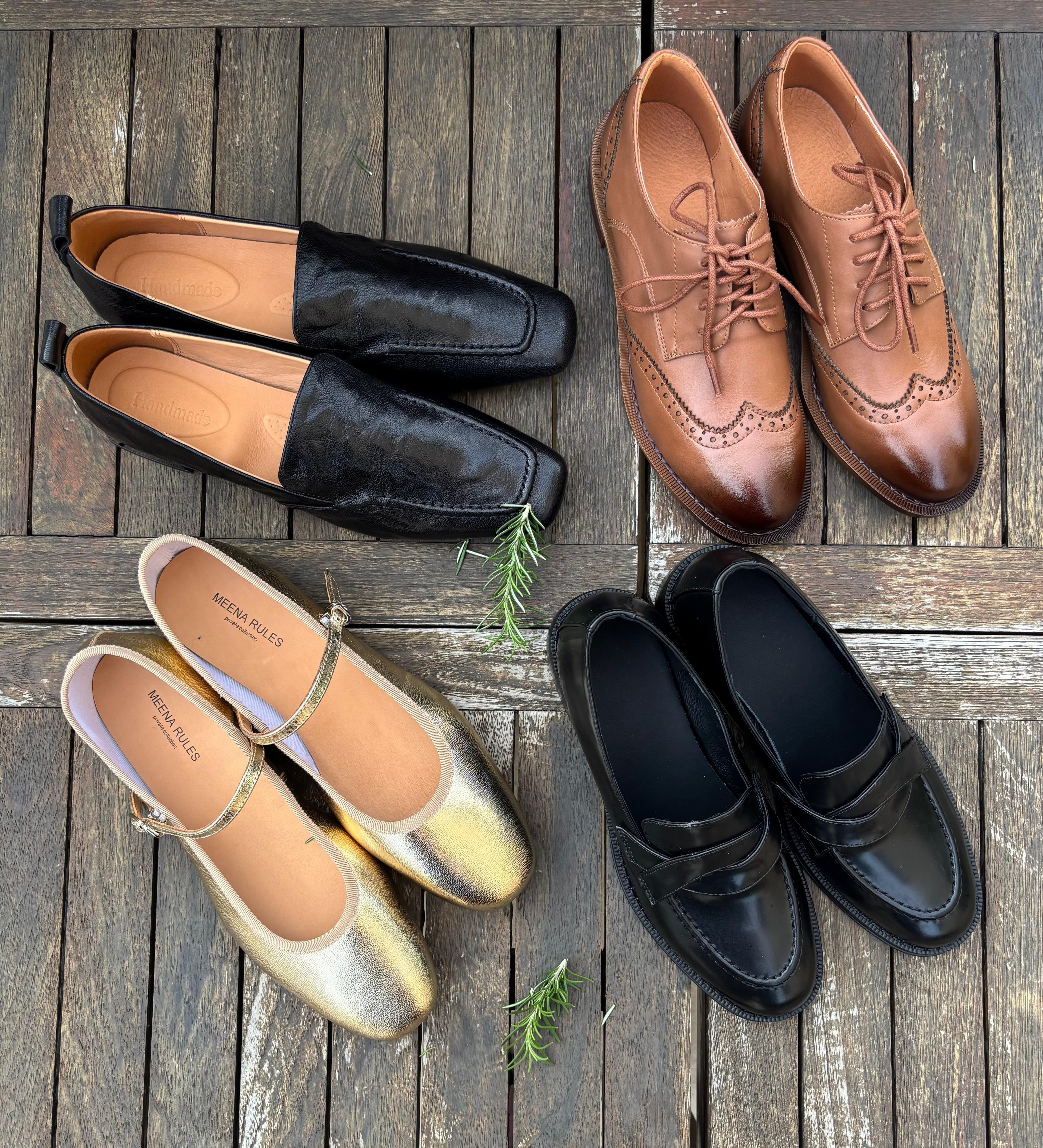 A flat-lay of handcrafted leather loafers, brogues, ballet flats, and slip-ons arranged on weathered wooden planks.
